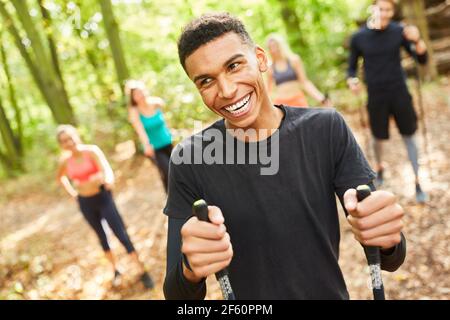 Ridendo giovane uomo mentre Nordic Walking con gli amici in natura in estate Foto Stock
