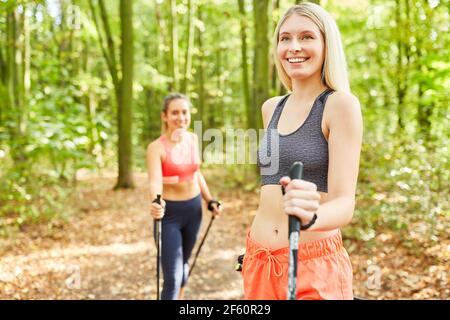 Due giovani donne allenano la loro forma fisica mentre si nordica camminando dentro l'aria fresca Foto Stock