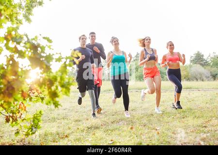 Gruppo di amici allenano la resistenza e il fitness mentre si corre da fondo in natura nel parco Foto Stock