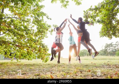 Gruppo di amici fa cinque in alto nel salto dopo un allenamento fitness insieme in estate Foto Stock