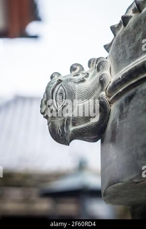 Primo piano di un dettaglio della testa di uccello su un grande censitore giapponese di metallo o bruciatore di incenso nel tempio di Kofukuji a Nara, Giappone Foto Stock