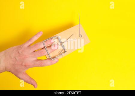 La mano dell'uomo è stata presa in un mousetrap su un background.Concept giallo, rischi e fallimenti Foto Stock