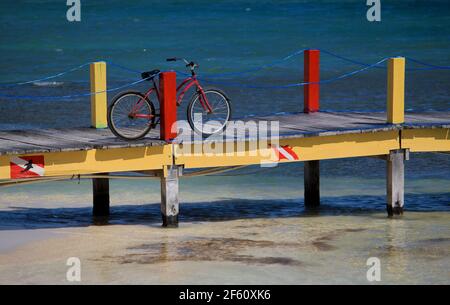 Bicicletta rossa sul molo colorato sull'oceano a San Pedro, Belize Foto Stock