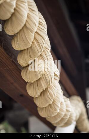 Primo piano dettaglio di Shimenawa, spezzoni di corda di paglia di riso posata utilizzati per la purificazione rituale nella religione Shinto fuori da un santuario a Nara, Giappone Foto Stock