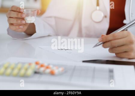 Donna-medico sconosciuto riempie in su la forma di prescrizione in stanza soleggiata, primo piano Foto Stock