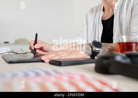 Le mani del progettista grafico che usano sulla tavoletta grafica durante il disegno logotipo per il cliente Foto Stock