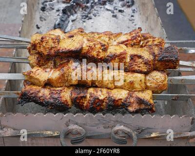 Carne strung su spiedini di metallo fritti su carbone all'aperto, primo piano Foto Stock