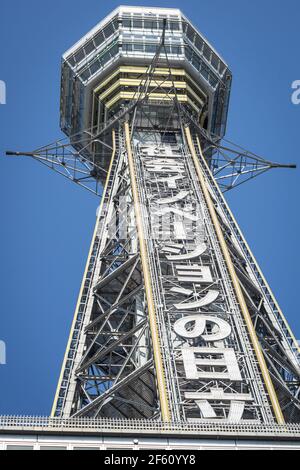 Vista della famosa Torre Tsutenkaku, a Shinsekai, Osaka, Giappone. Preso da sotto guardando in su in un cielo blu chiaro Foto Stock