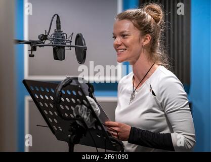 donna che registra voce, voce e canto in studio Foto Stock