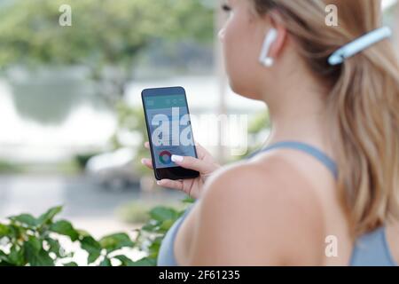 Giovane donna che usa l'applicazione sullo smartphone per controllare il suo peso e consumate e bruciate calorie Foto Stock
