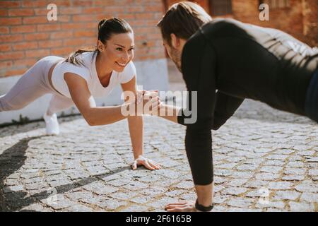 Bella giovane coppia doung un braccio pushup esercizio in ambiente urbano Foto Stock