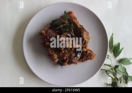 Arrosto di montone in stile Kerala preparato con olio di cocco. Scatto su sfondo bianco Foto Stock