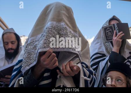 GERUSALEMME, ISRAELE - 29 MARZO: Gli adoratori ebrei si coprono di scialle di preghiera mentre pregano davanti al Muro Occidentale durante la messa biennale 'birkat kohanim' o 'benedizioni sacerdotali', durante la festa di Pasqua del 29 marzo 2021, a Gerusalemme, Israele Foto Stock