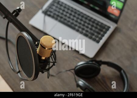 Primo piano del microfono e del computer portatile con le cuffie sul tavolo in studio di registrazione Foto Stock