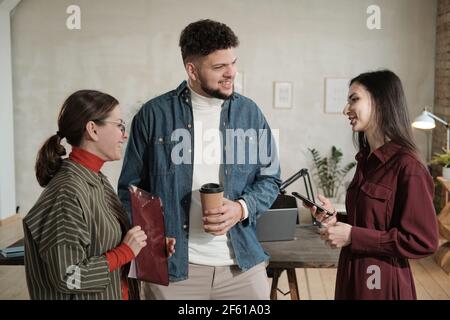 Gruppo di giovani uomini d'affari che parlano tra loro mentre in piedi in ufficio Foto Stock