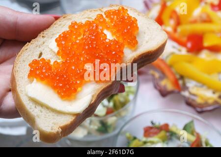 Sandwich con burro e abbondantemente coperto con stiva di caviale rosso dita Foto Stock