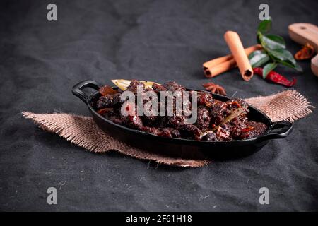 Arrosto di manzo o pothu ulartheyadu, piatto speciale kerala disposto in una tavola nera e in foglia di banana in modo tradizionale posto su un colore nero Foto Stock