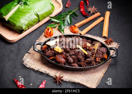 Arrosto di manzo o pothu ulartheyadu, piatto speciale kerala disposto in una tavola nera e in foglia di banana in modo tradizionale posto su un colore nero Foto Stock