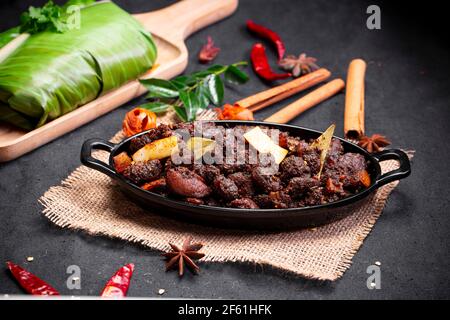 Arrosto di manzo o pothu ulartheyadu, piatto speciale kerala disposto in una tavola nera e in foglia di banana in modo tradizionale posto su un colore nero Foto Stock