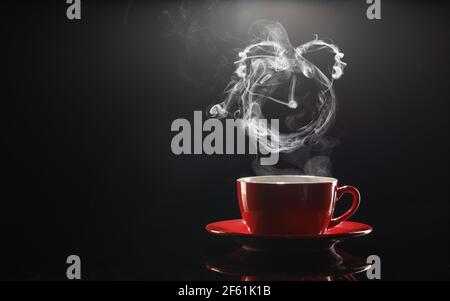 Tazza di caffè caldo e vapore sotto forma di sveglia orologio su sfondo scuro Foto Stock