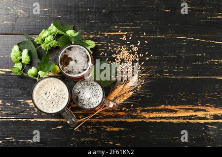 Tazze di birra fresca diversa su sfondo di legno scuro Foto Stock