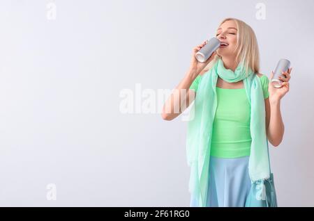 Bella giovane donna che beve soda su sfondo chiaro Foto Stock