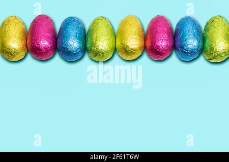 Uova di Pasqua al cioccolato avvolte in foglio. Colorato bordo dell'uovo di Pasqua. Foto Stock