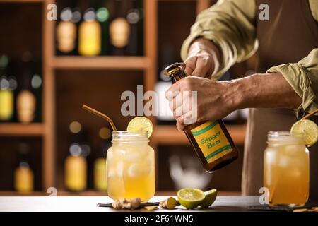 Barman con apertura bottiglia di birra fresca allo zenzero sul tavolo bar Foto Stock