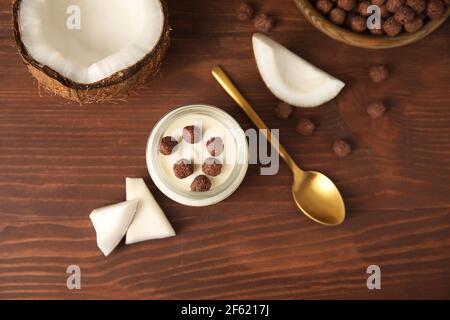 Vasetto di gustoso yogurt al cocco su sfondo di legno Foto Stock