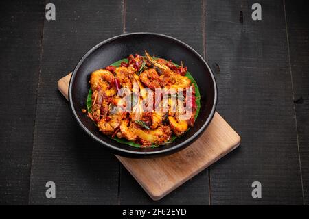 Kerala stile gamberi arrosto o chemmeen varattiyathu fatto con rosso fiocchi di peperoncino di kashmiri e fette di cocco come ingredienti principali e. guarnito con on Foto Stock