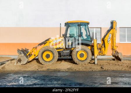 Bielorussia, Minsk - 19 dicembre 2019: Escavatore industriale sullo sfondo di un edificio moderno in un cantiere. Foto Stock