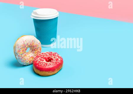Set di ciambelle colorate e tazzina di caffè su sfondo blu. Consegna online take away food Foto Stock