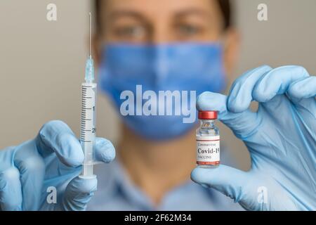 Il medico femminile contiene la siringa e il flaconcino di vaccino del coronavirus. Foto Stock