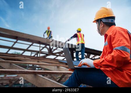 Tecnico tecnico tecnico addetto alla costruzione controlla il tetto che lavora sulla struttura del tetto dell'edificio in cantiere, conce di costruzione di lamiera del tetto Foto Stock