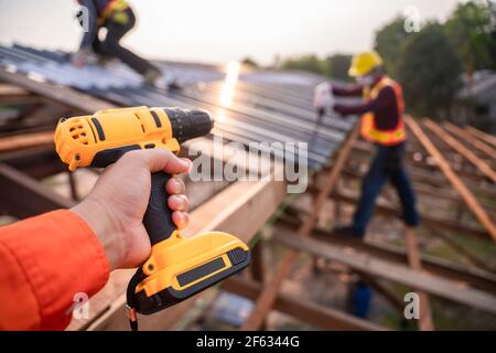 Messa a fuoco selettiva attrezzi per tetti, Roofer lavoratore che tiene trapano elettrico utilizzato su nuovi tetti con lamiera in cantiere. Foto Stock