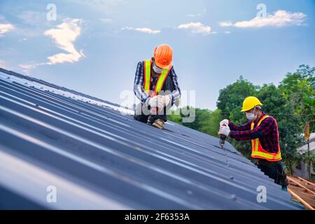 Team Work tetto concetto di edificio residenziale in costruzione, Roofer lavoratori di sicurezza indossare con aria o pistola pneumatica per unghie e l'installazione su nuovo ROO Foto Stock