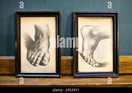 Set di due disegni vintage di piedi umani in diversi orientamenti in semplici cornici di legno nero indossate visualizzate su un ripiano Foto Stock