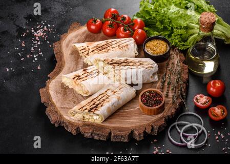 Delizioso shawarma fresco con carne e verdure su un tavolo di cemento scuro. Fast food, cucina turca Foto Stock