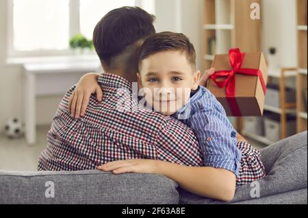 Carino bambino che dà presente al suo papà e desiderando Lui Felice giorno del Padre Foto Stock