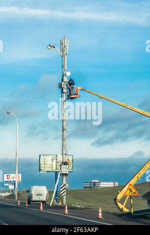 Bielorussia, Minsk - 19 dicembre 2019: Uomini industriali che lavorano su una gru a macchina che minaccia una linea elettrica. Foto Stock