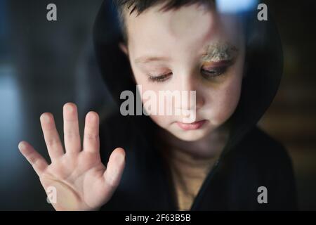 Povero ragazzo triste con sopracciglia tagliata in piedi in casa, concetto di povertà. Foto Stock