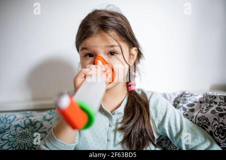 Ritratto di bambina malata a casa, con l'inalatore. Foto Stock