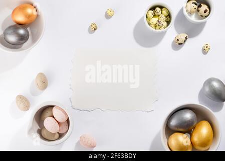 Molte uova di Pasqua multicolore in ciotole di diverse misure su uno sfondo bianco Foto Stock