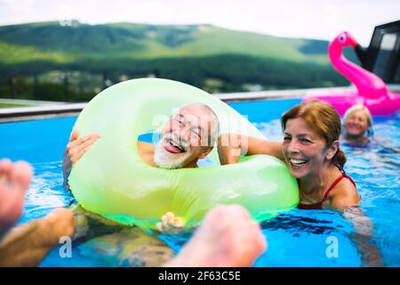 Gruppo di anziani allegri in piscina all'aperto in cortile, divertirsi. Foto Stock