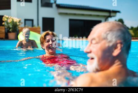 Gruppo di anziani allegri in piscina all'aperto in cortile, divertirsi. Foto Stock