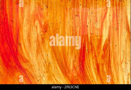 particolare di un vetro appartenente ad una vetrata con tinte arancioni scure e chiare e alcune bolle all'interno esso Foto Stock