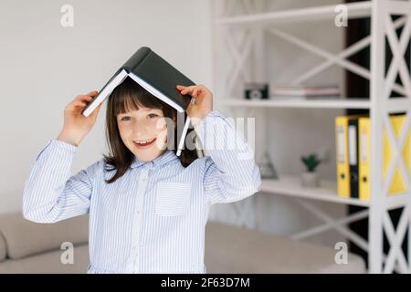 Ritratto di bella ragazza pre-teen attraente che fa attività di lavoro domestico di classe nel soggiorno al divano. Istruzione Foto Stock