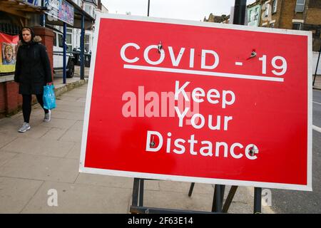 Londra, Regno Unito. 29 marzo 2021. Una donna cammina oltre un cartello con la scritta 'COVID-19, Keep your distance' a Londra. (Foto di Dinendra Haria /SOPA Images/Sipa USA) Credit: Sipa USA/Alamy Live News Foto Stock