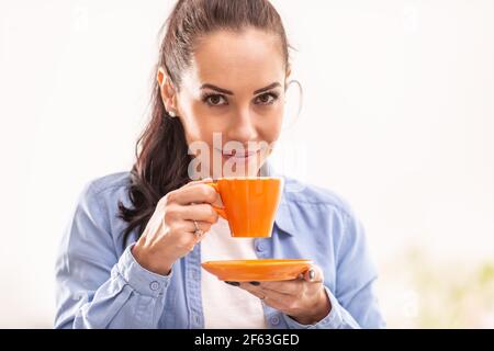 La bella donna puzzava di caffè fresco di un bicchiere d'arancia. Foto Stock