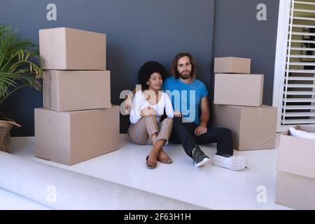 Felice diversa coppia commovente casa seduta e abbracciando Foto Stock